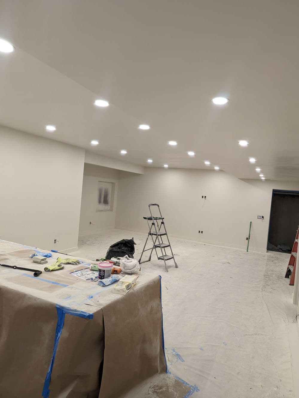 Brightly lit modern interior room during renovation with ladder and tools visible.