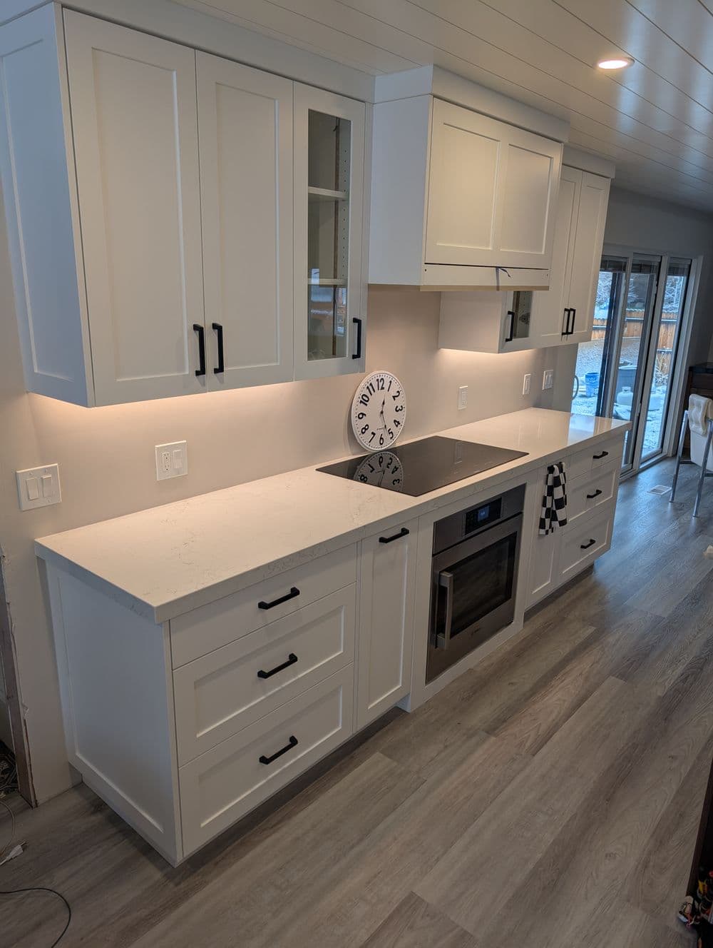 Modern kitchen with white cabinets, quartz countertop, stainless steel appliances, and large windows.