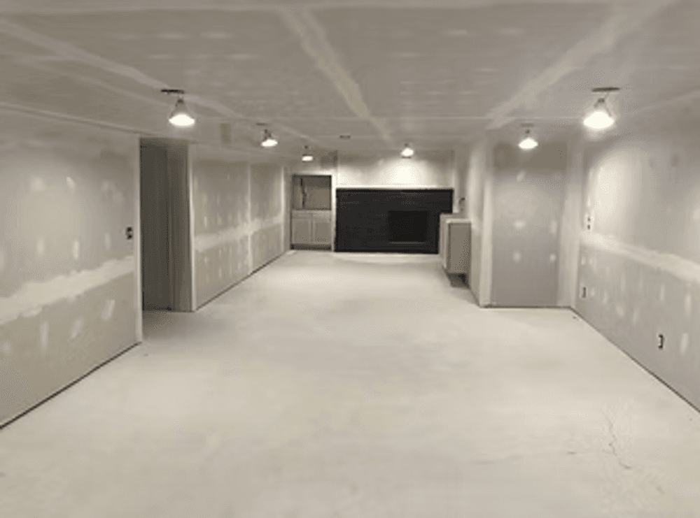 Spacious unfinished basement with drywall and ceiling lights, ready for final renovation.